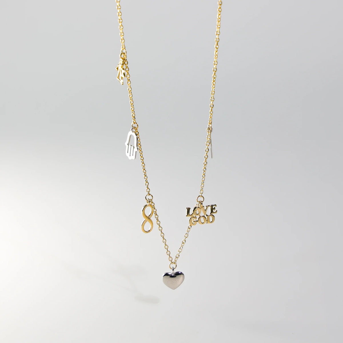 Gold necklace with various charms on a light gray background available on the TX.ORO website.
