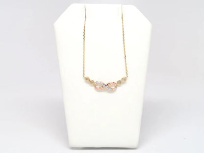 Necklace with pink beads on a white stand against a light gray background available on the TX.ORO website.