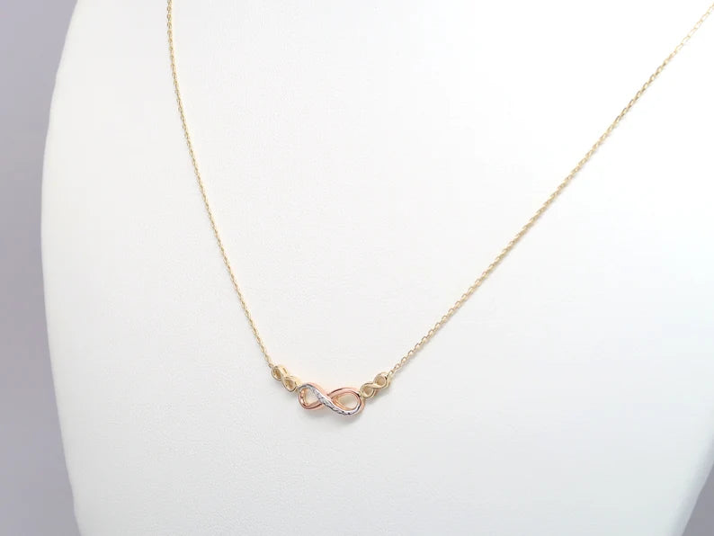 Gold necklace with a pink heart pendant on a white stand available on the TX.ORO website.