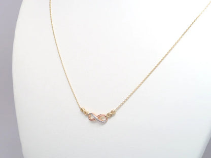 Gold necklace with a pink heart pendant on a white stand available on the TX.ORO website.