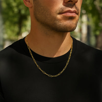 Man wearing a gold chain necklace with a blurred green outdoor background available on the TX.ORO website.