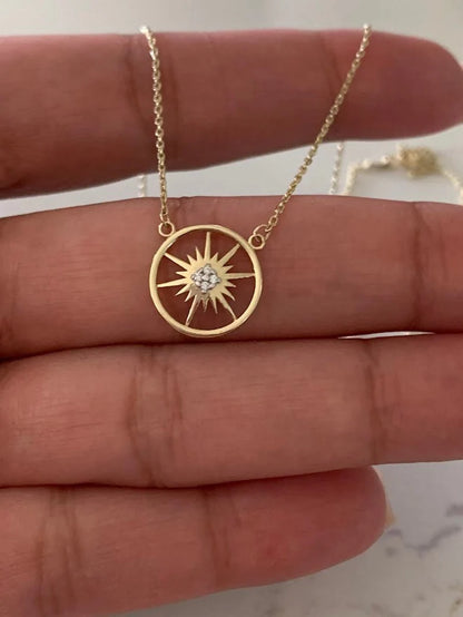Gold necklace with a sun-shaped pendant on a hand available on the TX.ORO website.