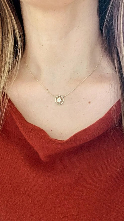 Necklace with a small round pendant worn by a person in a red top available on the TX.ORO website.