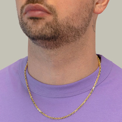 Man wearing a gold chain necklace against a plain background available on the TX.ORO website.