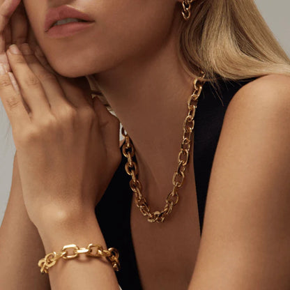 Woman wearing a gold chain necklace and bracelet against a neutral background available on the TX.ORO website.