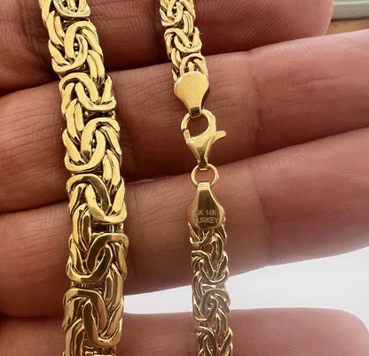 Gold chain necklace held by a hand with a clear background available on the TX.ORO website.