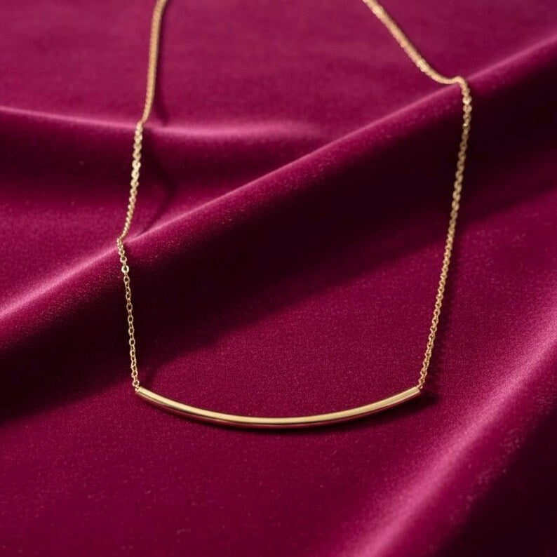 Gold necklace on a burgundy fabric background available on the TX.ORO website.