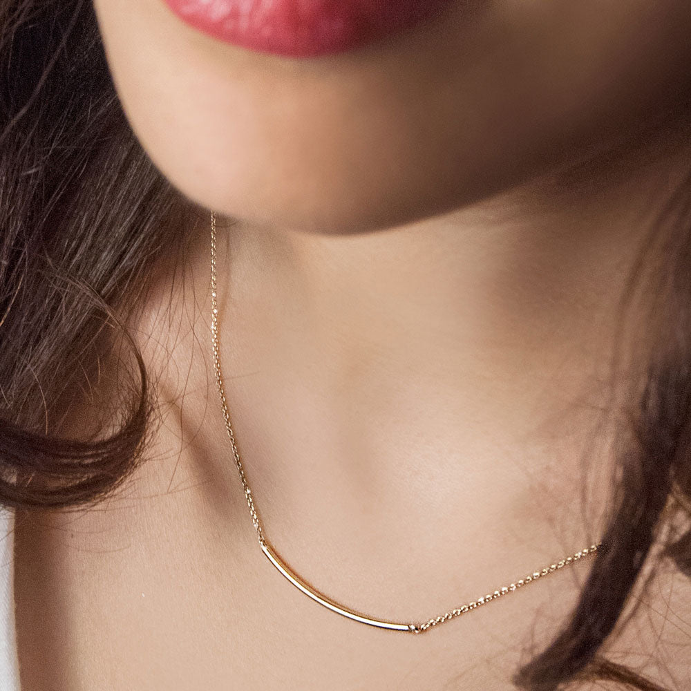 Gold necklace worn by a person with a blurred background available on the TX.ORO website.