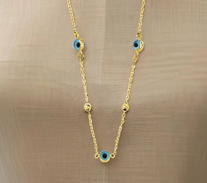 Gold necklace with blue evil eye charms on a beige background available on the TX.ORO website.