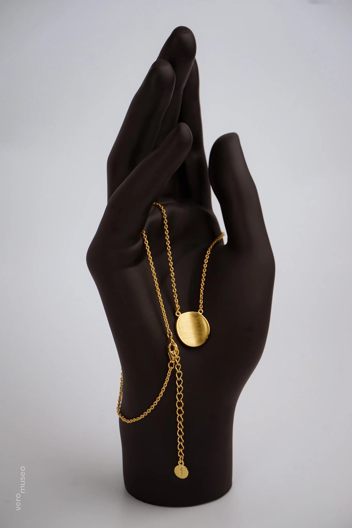 Gold necklace on a black mannequin hand against a gray background available on the TX.ORO website.
