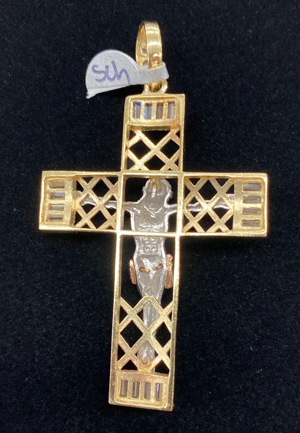Gold cross pendant with a figure on a black background 