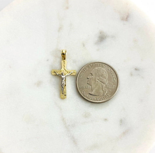 Gold crucifix pendant next to a quarter on a marble surface