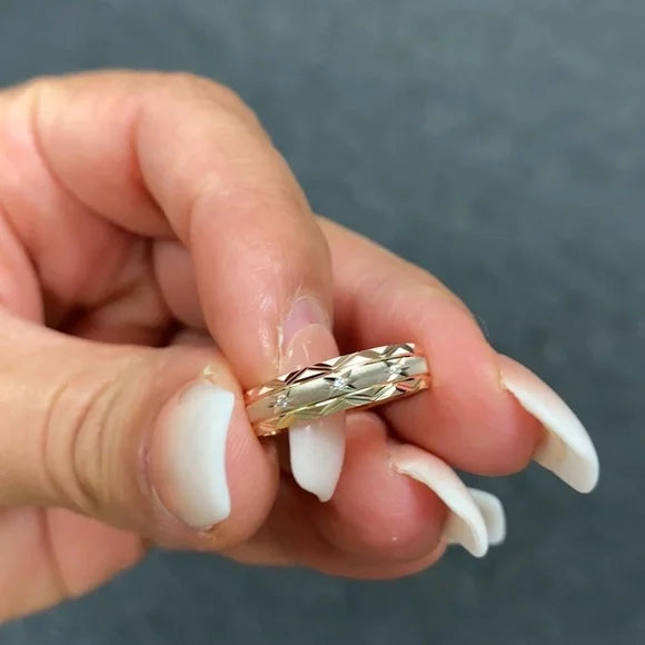 Gold ring being held between fingers against a neutral background