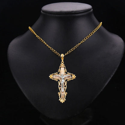 A gold cross pendant necklace with clear rhinestones, displayed on a black mannequin bust against a black background.